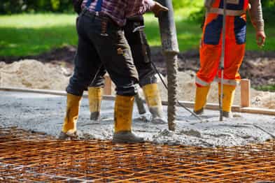 Three people lay concrete to build a road